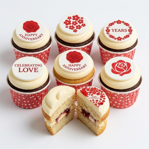 Anniversary cupcakes with red rose and floral edible toppers on white icing and red polka dot cases.