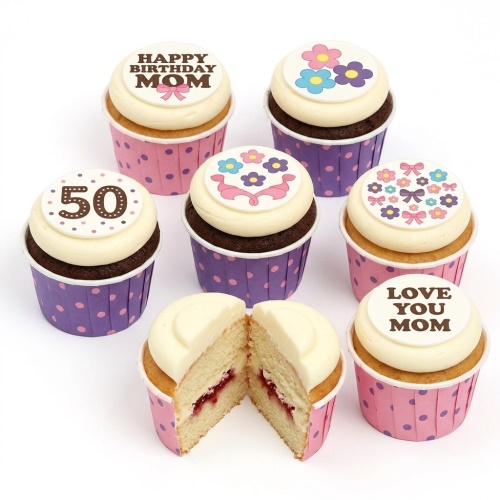 White frosted cupcakes with pink and purple polka dot wrappers, decorated with edible floral designs, bows, and messages for a custom age birthday.