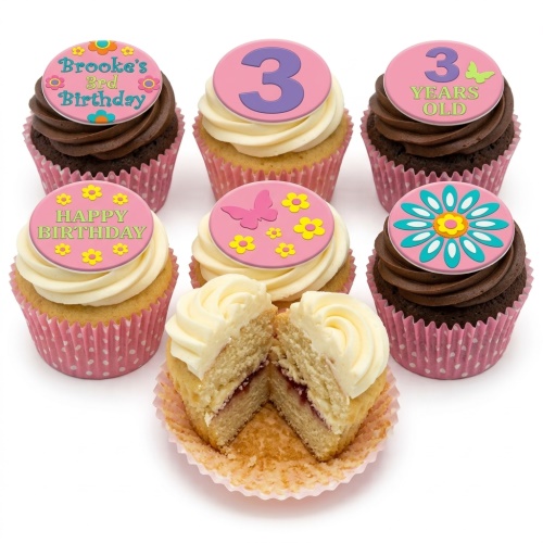 Assortment of kids birthday cupcakes with pink, yellow, blue floral and butterfly toppers, and custom age number 3.