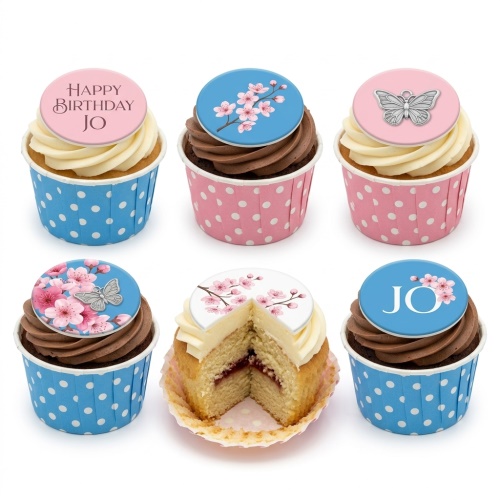 A selection of floral and butterfly themed birthday cupcakes with pink and blue polka dot wrappers.
