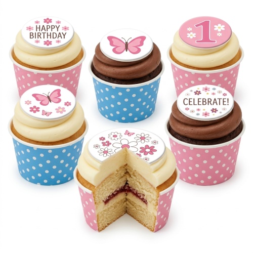 Six cupcakes with pink and blue polka dot wrappers, topped with white frosting and edible butterfly and floral discs, one showing 'Happy Birthday' and another '1'.