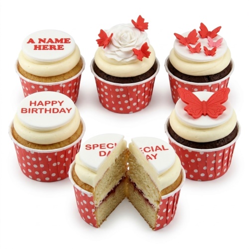 Assortment of butterfly and rose birthday cupcakes with custom message toppers in red polka dot wrappers.