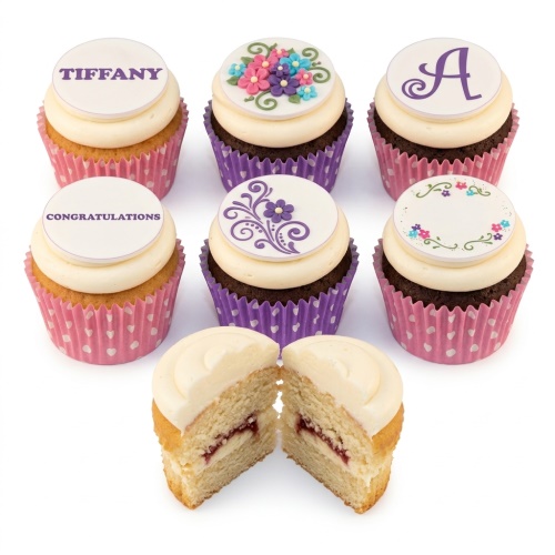 Six elegant cupcakes with various floral designs and customisable message toppers, presented in pink heart and purple polka dot wrappers.