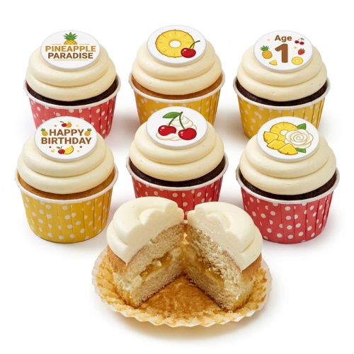 Tropical pineapple and cherry themed cupcakes with white frosting and polka dot wrappers, one cut open.