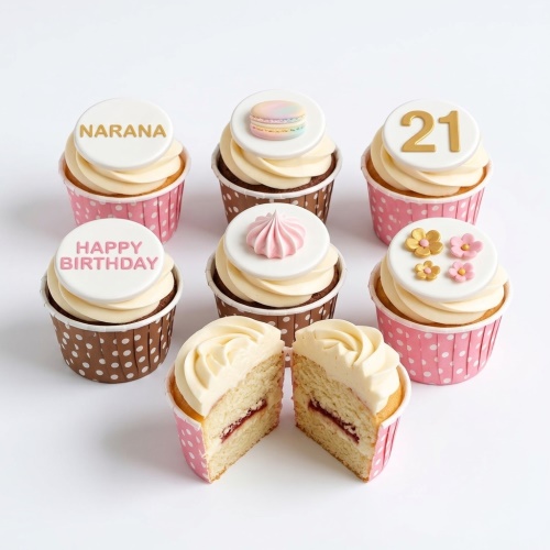 Assortment of elegant birthday cupcakes with cream frosting, pink and gold sugar flowers, pastel macaron, pink meringue, and customisable name and age toppers.