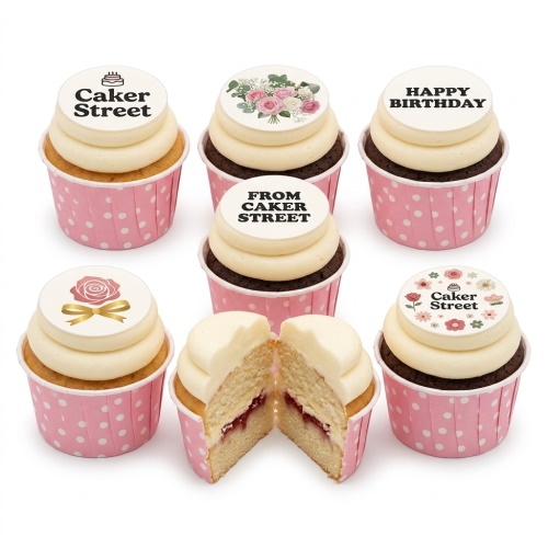 Assortment of cupcakes with white icing and edible floral toppers in pink polka dot wrappers.