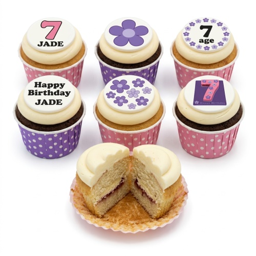 Assortment of floral birthday cupcakes with purple flowers and custom age topper for a girl.