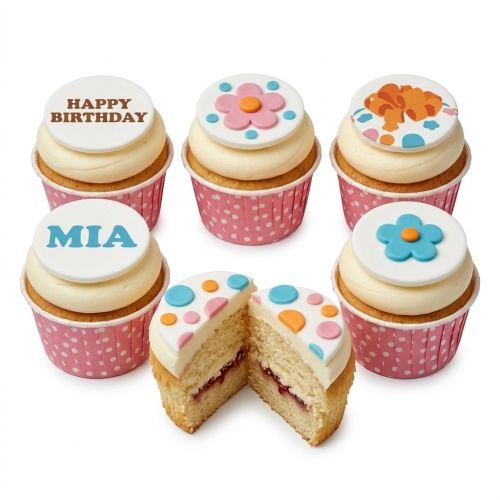 Cupcakes with cream frosting, decorated with white fondant toppers featuring pink and blue flowers, orange bows, and polka dots, in pink polka dot wrappers.