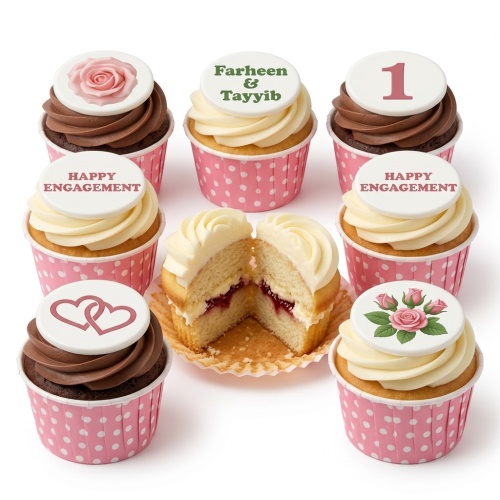 Assortment of vanilla and chocolate engagement cupcakes with floral, heart, and custom message toppers in pink wrappers.