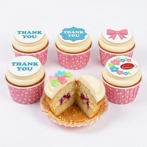 Selection of thank you cupcakes with white icing, pink polka dot cases, and decorative toppers.