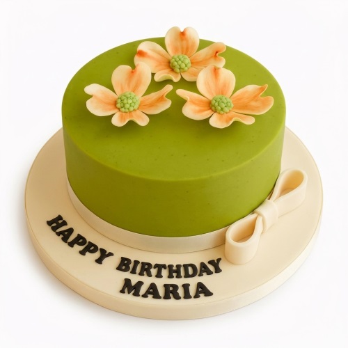 Round green fondant cake with three peach and green sugar flowers on top, a cream ribbon, and a bow on the cake board.