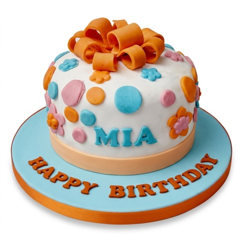 White round birthday cake with orange bow, pink, blue, and orange polka dots and flowers.
