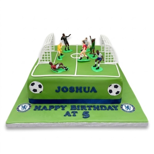 Green football pitch cake with Chelsea FC logos, player figures, and goalposts for a custom age birthday.