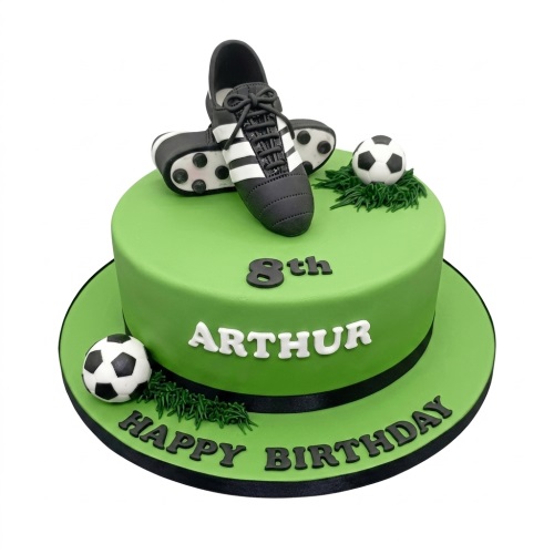 Green birthday cake with edible football boots, two footballs, and custom age and name.