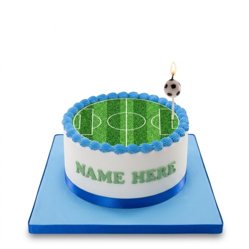 Round white cake with a green football pitch top, blue piped border, blue ribbon, and a football candle. Personalised "NAME HERE" text on side.