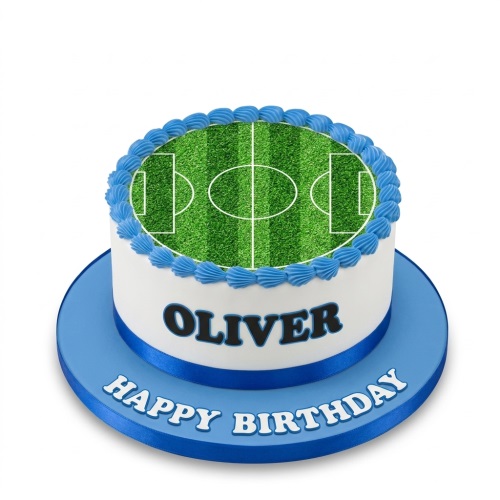 Round white birthday cake with edible football pitch top, blue piping, blue ribbon, and custom name.