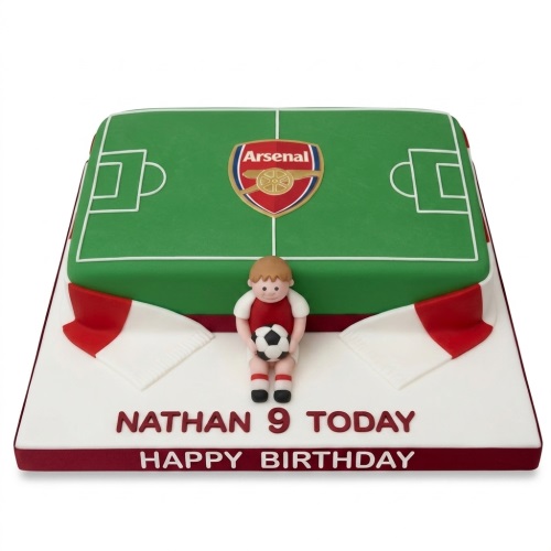 Rectangular two-tier Arsenal football pitch birthday cake with a boy figurine, flags, and custom message.