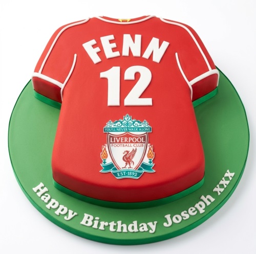 Red Liverpool football shirt birthday cake with custom name and number, on a green base.