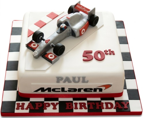 Square white fondant cake with a silver and red Formula 1 racing car, red and white track markings, and a black and white checkered flag cake board.