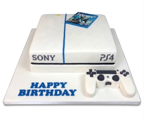 White PS4 console birthday cake with edible controller and Fortnite game case, with a 'Happy Birthday' message.