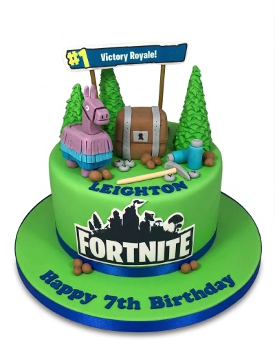 Green Fortnite themed birthday cake with a Llama, treasure chest, pickaxe, trees, and a 'Victory Royale!' sign, with space for custom name and age.