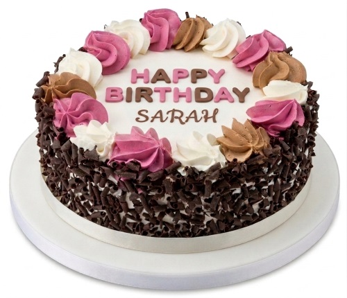 Round white birthday cake with chocolate shavings, pink, brown, and white frosting swirls, and 'Happy Birthday' message.