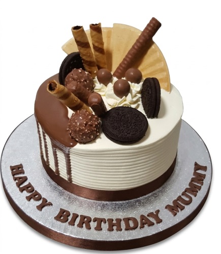 Round chocolate drip birthday cake with chocolate wafer rolls, Oreo biscuits, and chocolate balls.