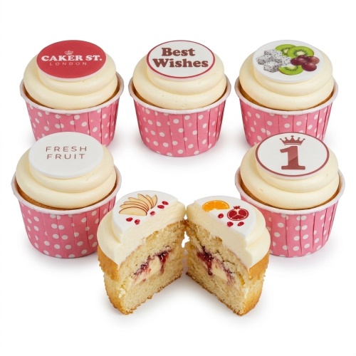 Six cupcakes with white frosting, pink polka dot cases, and edible toppers featuring fruit, "Best Wishes", "Fresh Fruit", and a number 1 with a crown.