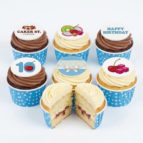 Assortment of birthday cupcakes with fruit toppers, a custom age topper, and a personalised message, in blue polka dot cases.