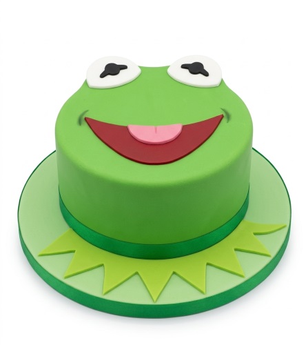 Green frog-themed birthday cake with white eyes, red mouth, and pink tongue.
