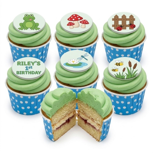 Six cupcakes with green frosting and nature-themed edible toppers including a frog, mushrooms, ladybugs, a dragonfly, and bees, in blue polka dot cases.