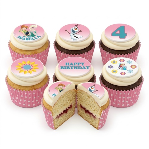 A selection of Disney Frozen themed cupcakes with white frosting and pink polka dot wrappers, featuring edible toppers of Anna, Elsa, Olaf, a sunflower, a 'Happy Birthday' message, and a number '4' topper. One cupcake is cut in half revealing a vanilla sponge with jam filling.