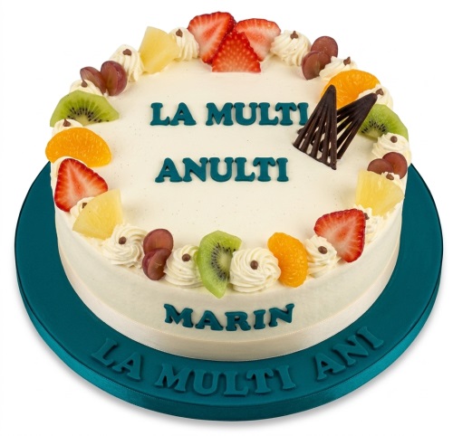 Round fresh fruit birthday cake with cream swirls and chocolate decorations on a teal board.