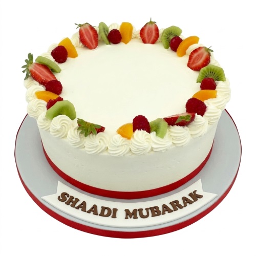 Round white cake decorated with fresh strawberries, kiwi, raspberries, and orange fruit slices, with a red ribbon.