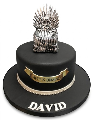 Black single-tier Game of Thrones themed birthday cake with a silver Iron Throne topper, custom age banner, and personalised name.