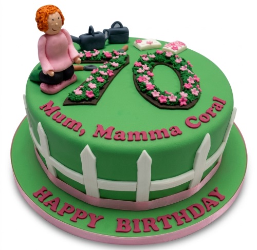 Green gardening theme birthday cake with female figurine, floral custom age numbers, and white picket fence.