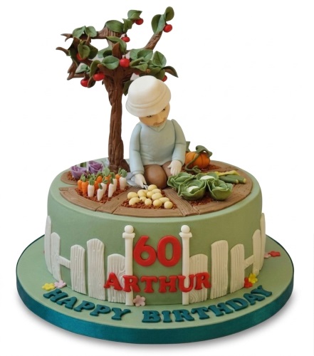 Round gardening theme birthday cake with gardener figure, tree, vegetables, fence, and custom age.