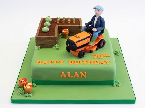 Square green birthday cake with a man on a lawnmower and raised garden beds.