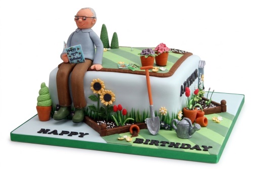 Novelty gardening theme birthday cake with an old man figurine, shovel, watering can, and flowers.
