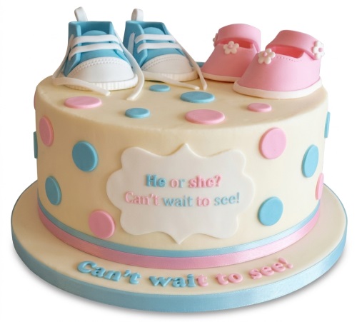 Round gender reveal cake with blue and pink baby shoes, polka dots, and "He or she?" message.