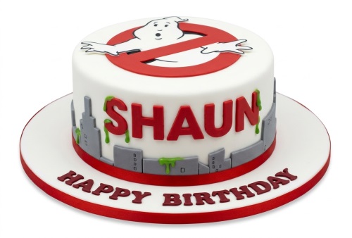 White round Ghostbusters birthday cake with logo, city skyline, green slime, and custom name.