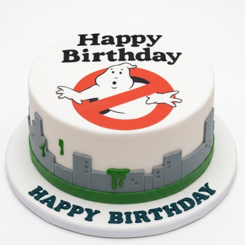 Round white Ghostbusters birthday cake with logo, city skyline, and green slime.