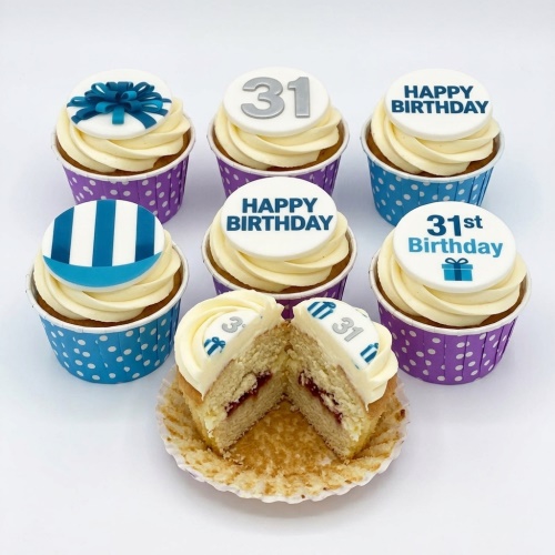 Six custom age birthday cupcakes with white frosting, blue and purple cases, and blue/silver toppers.