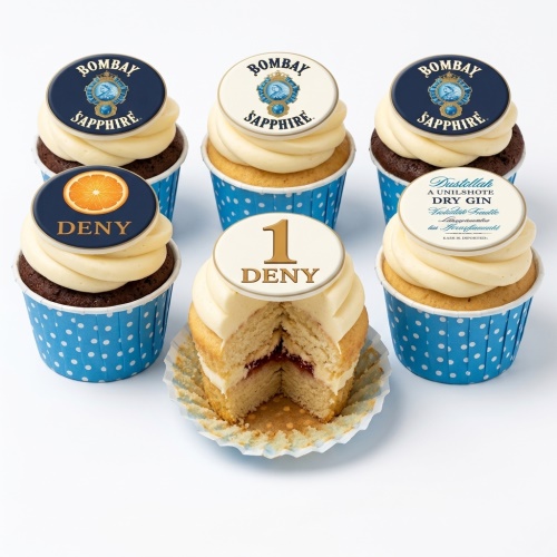 Six cupcakes with white frosting, blue polka dot cases, and edible toppers. Toppers include Bombay Sapphire logos, an orange slice with 'DENY', and a '1 DENY' design.