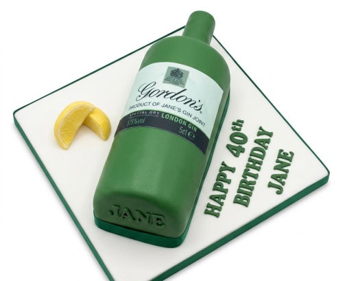 Green gin bottle shaped birthday cake on a white board with lemon slices and custom message.