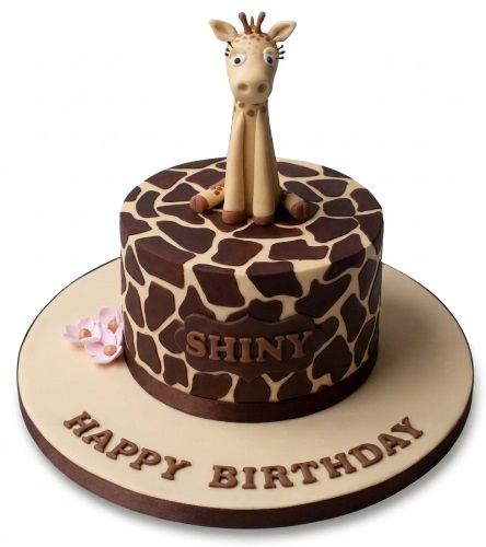 Round birthday cake with giraffe print, 3D giraffe topper, and small pink flowers.