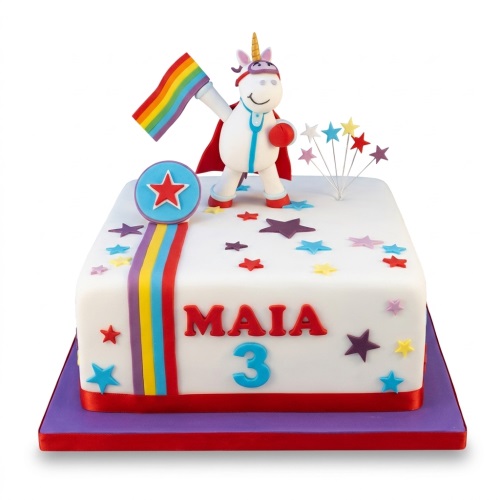 White rectangular cake with a superhero unicorn holding a rainbow flag, rainbow stripe, and colourful stars.