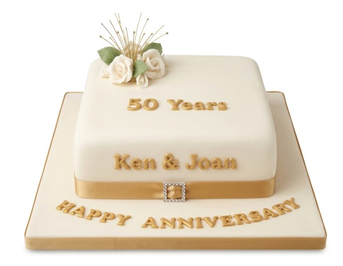 Elegant white square cake with gold '50 Years' and 'Happy Anniversary' text, gold ribbon, diamante buckle, and white sugar roses.