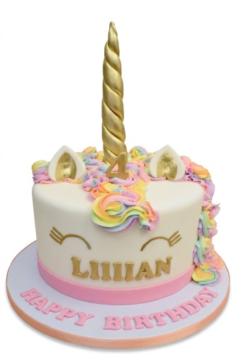 White unicorn birthday cake with gold horn, rainbow mane, and custom age topper.