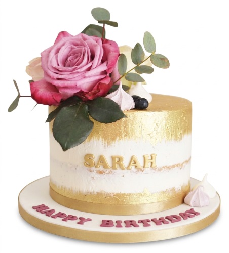 Elegant semi-naked cake with gold leaf, pink rose, eucalyptus, meringues, and personalised name.